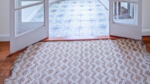 A view through open French doors into a covered patio area with a patterned floor and a wooden deck. - Bellport Inn (Bellport)