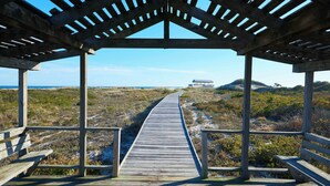 A wooden boardwalk leading to a beach area with a covered pavilion. - Bellport Inn (Bellport)