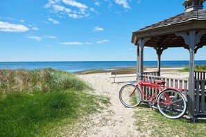 A beach scene with a wooden gazebo, a red bicycle, and a bench.