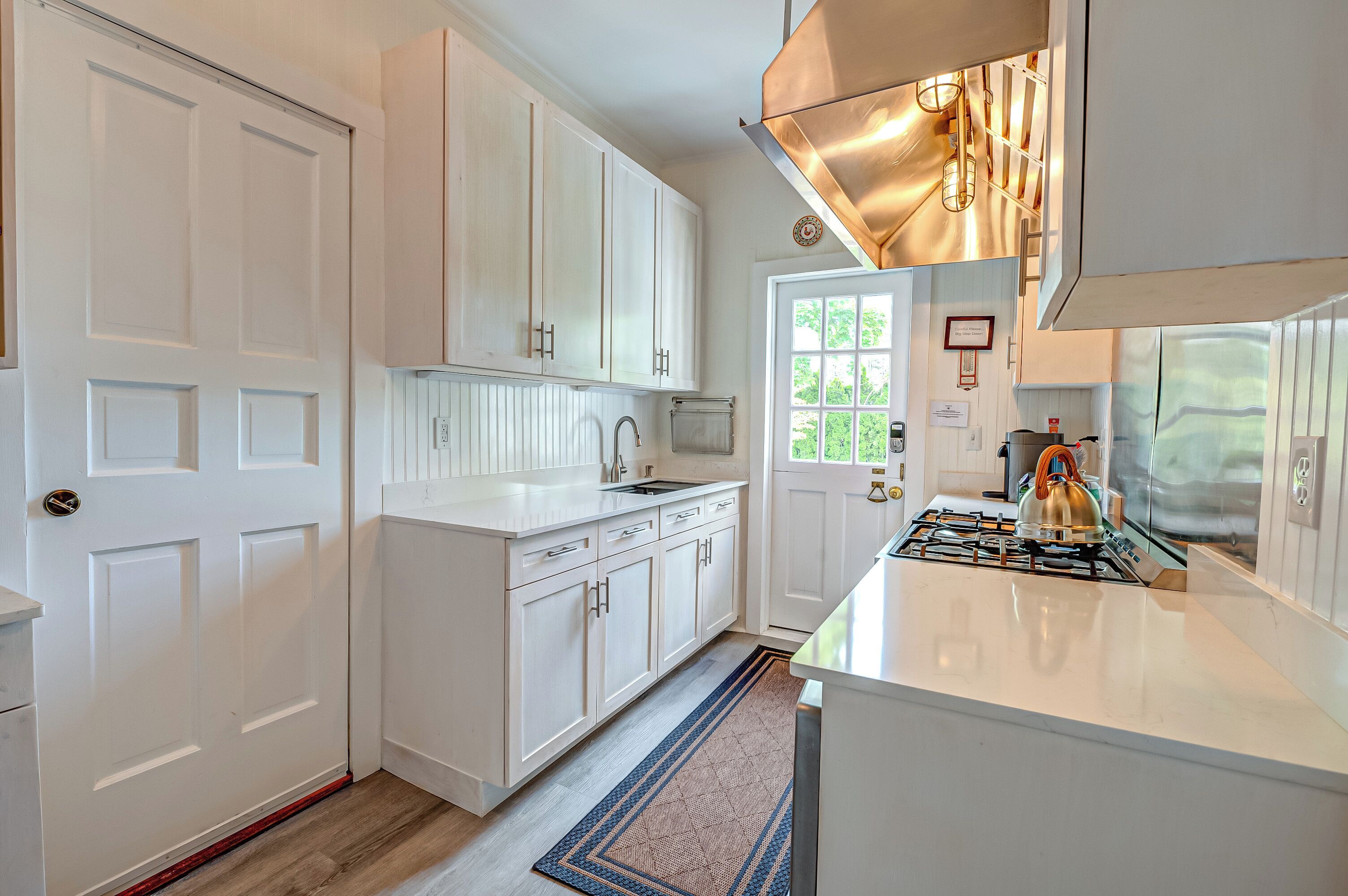 A modern kitchen with white cabinetry, a stainless steel range hood, and a gas stove.
