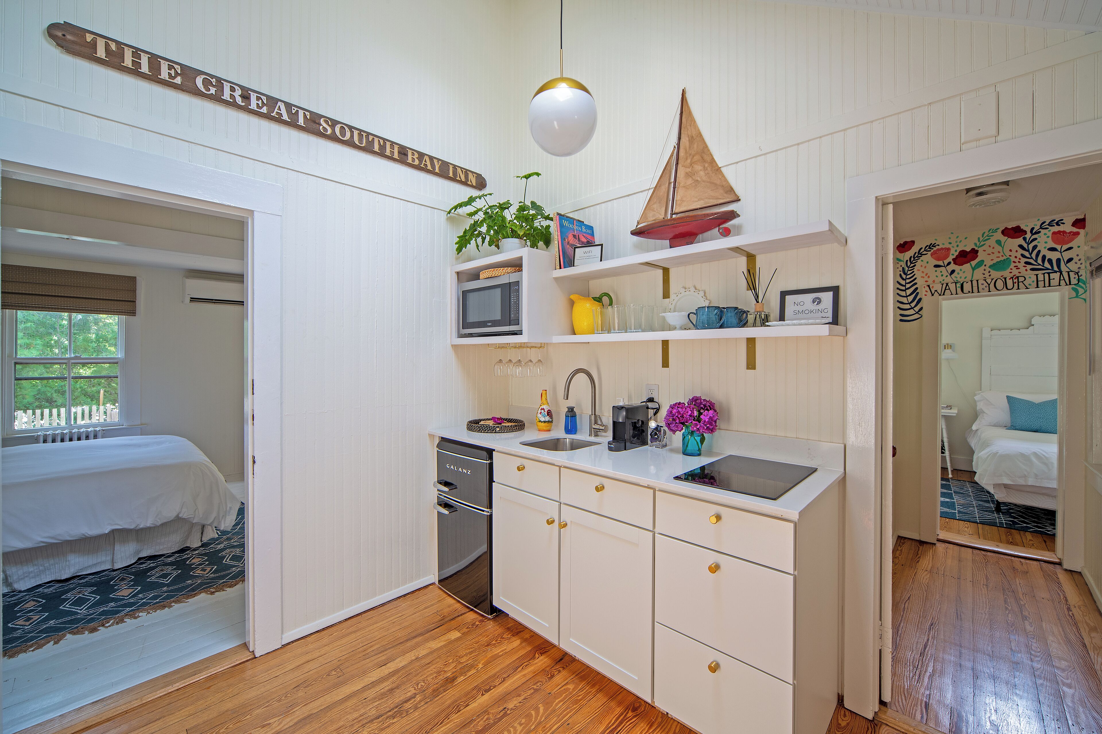 A compact hotel room with a kitchenette, a bed, and a view of the outdoors.