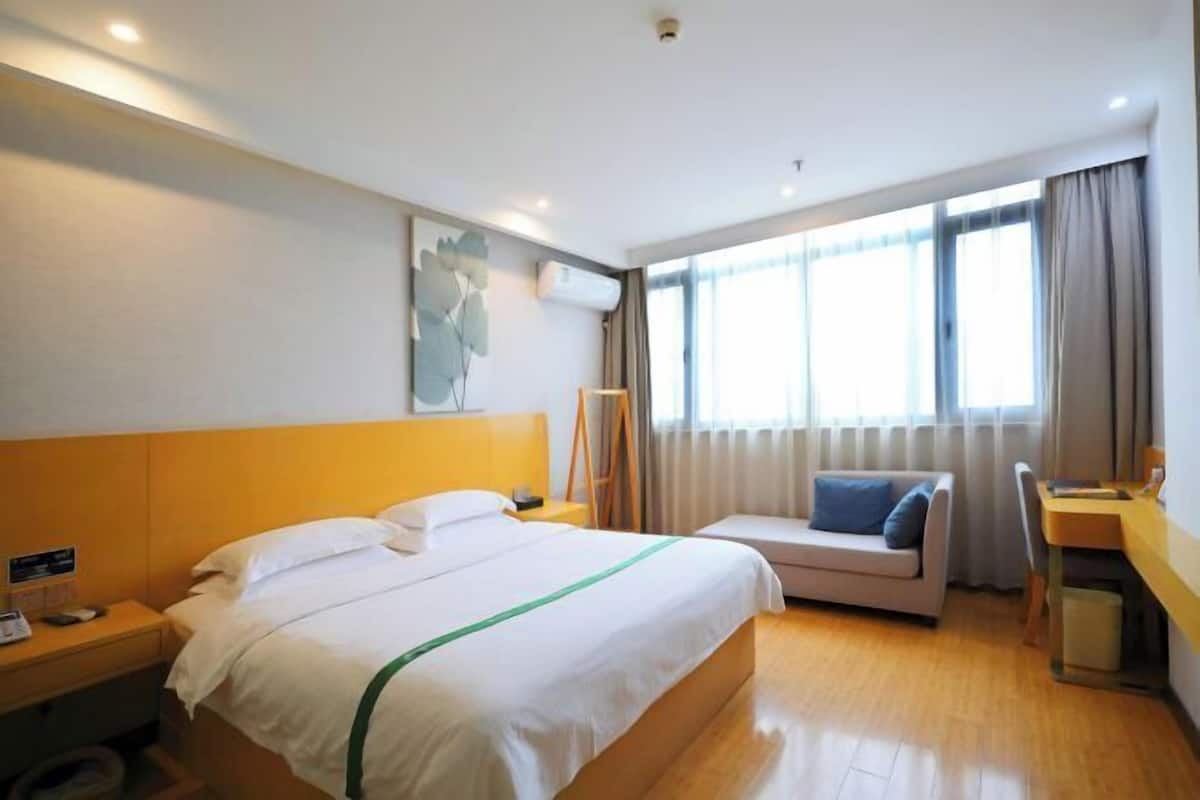 A hotel room with a bed, a sofa, a desk, and a window with curtains.