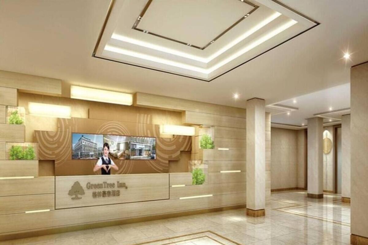 A hotel reception area with a modern design, including a reception desk, a large screen, and a well-lit interior.