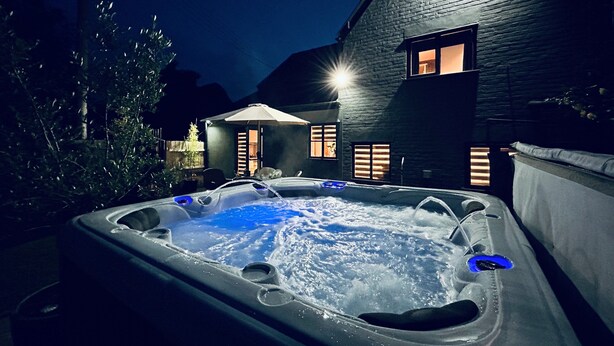 Ein Whirlpool im Garten, mit einem Haus im Hintergrund.