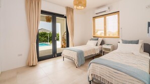 A bedroom with two beds, a large window, and a view of a swimming pool. - Villa Coastal Bliss with private pool & sea view at Jan Thiel (Jan Thiel)