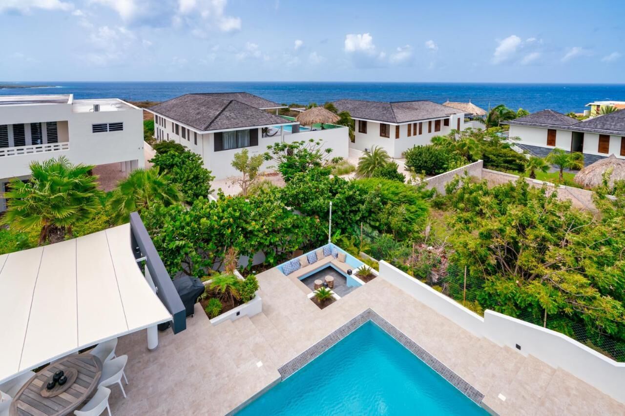 A resort with a swimming pool, outdoor seating, and views of the ocean.