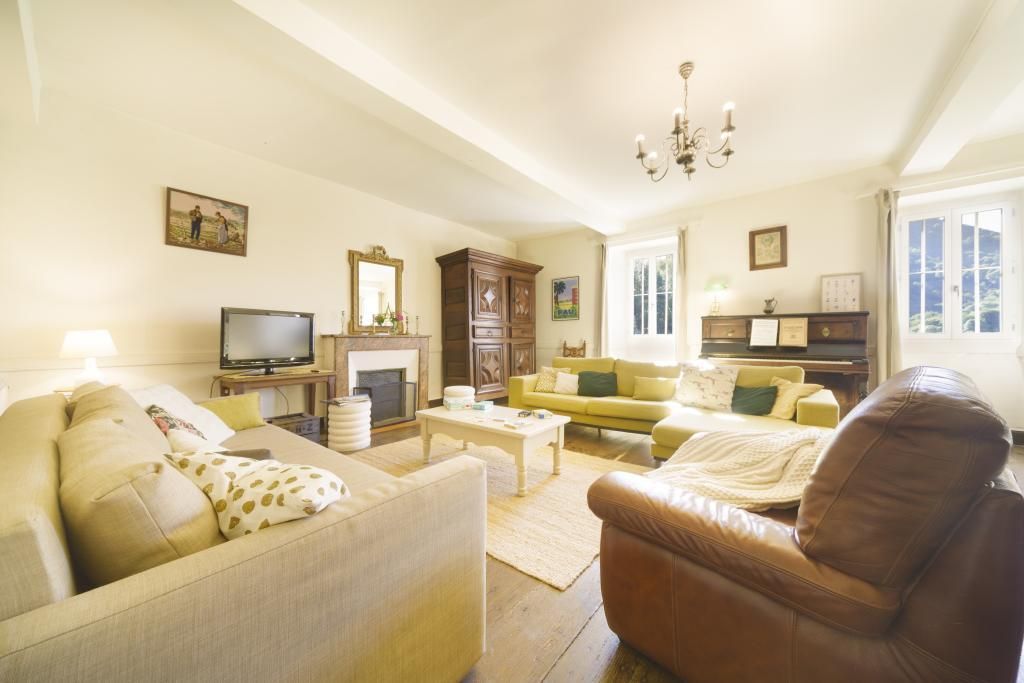 A living room with a fireplace, sofas, a television, and a chandelier.