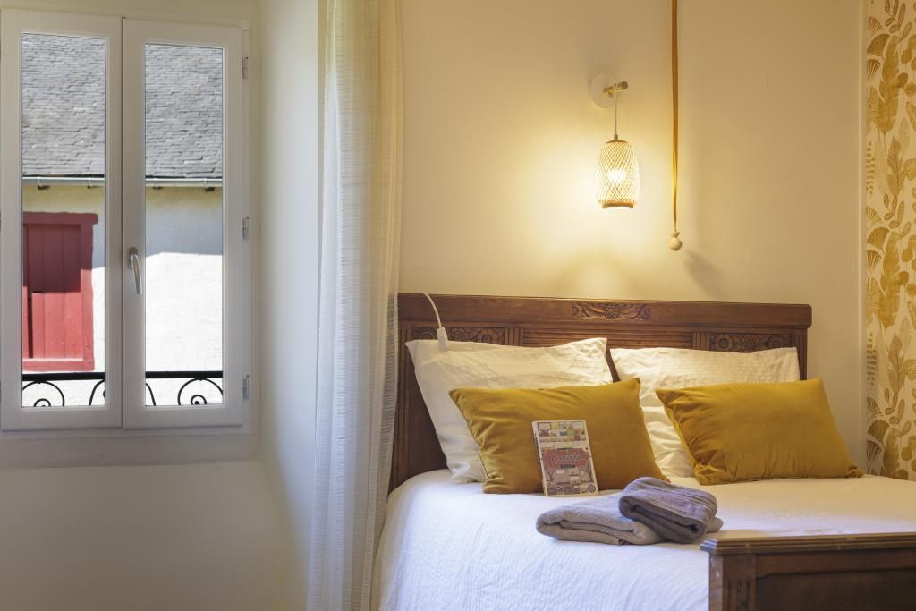 Een bed met een houten hoofdbord, witte beddengoed en twee gele kussens.