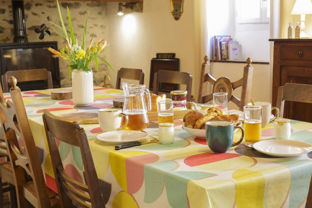 A dining table set with various breakfast items, including a pitcher, cups, and a bowl of pastries.
