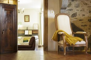 A room with a wooden door, a brown leather sofa, a white armchair with a yellow throw, and a tiled floor. - At Jeanne's: A one-of-a-kind view, complete privacy   (ISSOR)