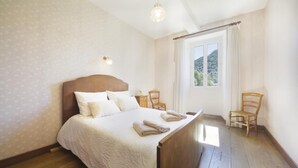 A bedroom with a wooden bed, a window with a view, and a chair. - At Jeanne's: a one-of-a-kind view, absolute privacy (ISSOR)