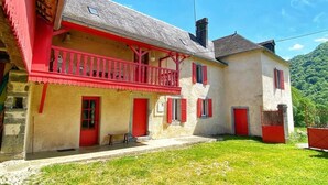 Un immeuble de deux étages avec un balcon rouge et des portes rouges.