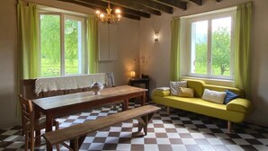 Une pièce comprenant un banc en bois, un canapé jaune, une table en bois et un lustre.