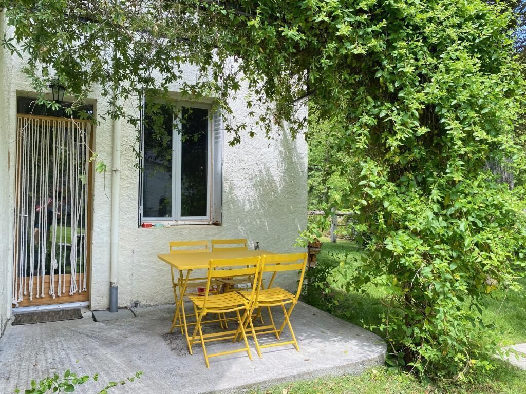A patio with a yellow table and chairs, a window, and a door with a curtain.