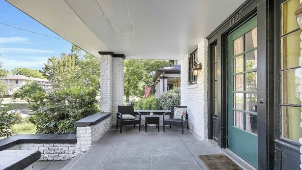 A covered patio with a table and chairs, a stone wall, and a green door. - Sleeps 12 • Budget-Friendly Downtown Birmingham Crew House (Birmingham)