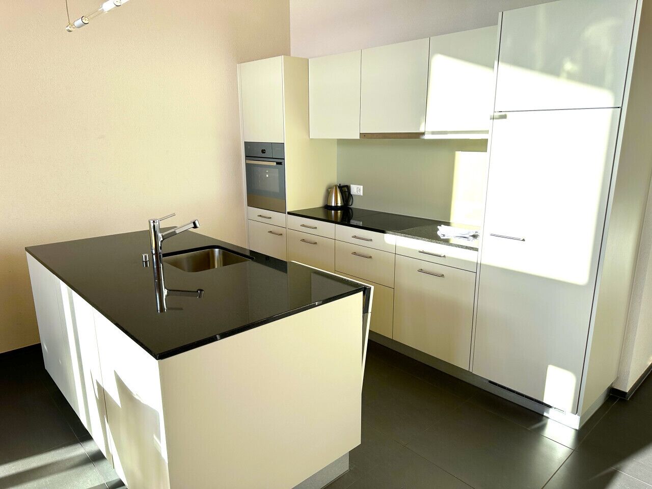 A modern kitchen with a black countertop, white cabinets, and a built-in oven.