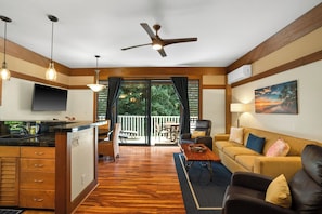 A modern kitchen with a TV, wooden cabinets, and a dining area with a table and chairs.