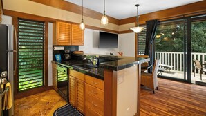 Una cocina con armarios de madera, encimera negra y un ventanal amplio.
