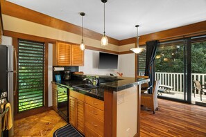 A kitchen with wooden cabinets, a black countertop, and a large window.