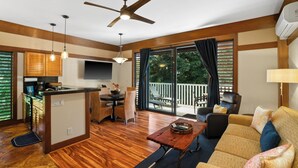Un espacio habitable amplio con piso de madera, ventilador de techo, mesa de comedor y sofá.