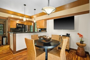 A modern kitchen with wooden cabinets, a black countertop, and a dining area with wicker chairs and a round table.
