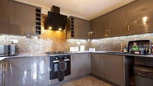 Una cocina moderna con electrodomésticos de acero inoxidable, un salpicadero con estampado de espiga y suelo de madera.