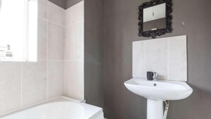 Un baño con bañera, lavamanos y espejo.