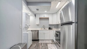 A modern kitchen with white cabinets, stainless steel appliances, and a wooden floor. - Cozy Apartment in Lilburn - Unit A + Unit C (Lilburn)