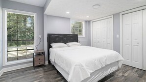 A bedroom with a bed, a nightstand, a window, and a wardrobe. - Cozy Apartment in Lilburn - Unit A + Unit C (Lilburn)