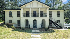 A two-story building with a central entrance, arched windows, and a staircase on the right. - Cozy Apartment in Lilburn - Unit A + Unit C (Lilburn)