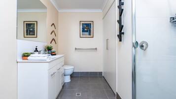 Un baño moderno con inodoro, lavamanos y cabina de ducha.