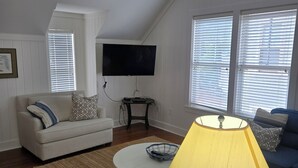 Ein Wohnzimmer mit Deckenventilator, Flachbildfernseher, Couchtisch, Sofa und einer Lampe.