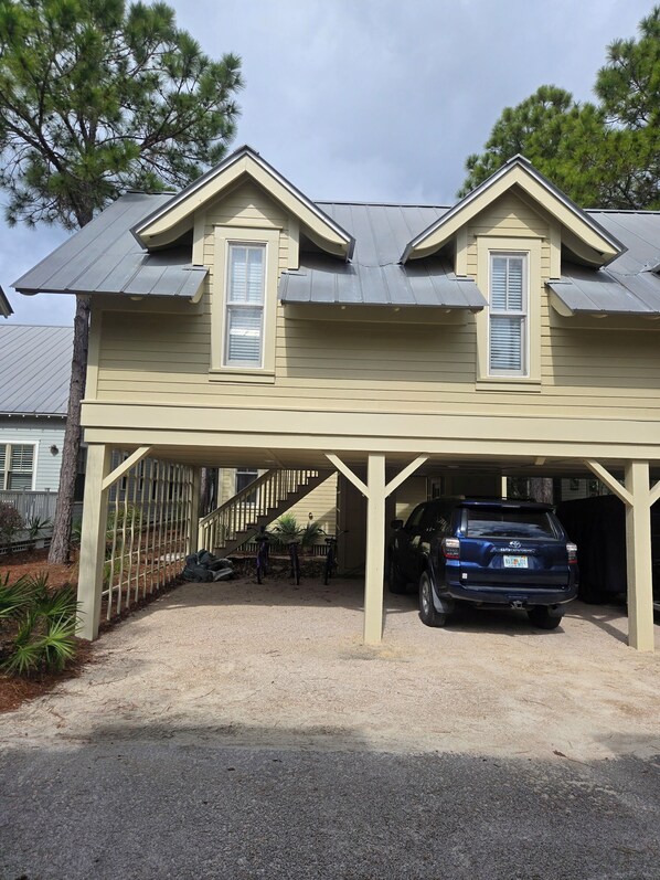 A two-story house with a covered garage and a staircase leading to the second floor. - Charming carriage house in marvelous Watercolor. (Santa Rosa Beach)