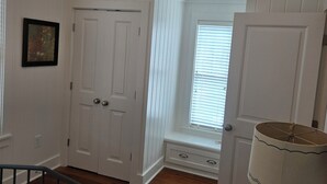 Ein Schlafzimmer mit Bett, Fenster mit Jalousien, einer Tür und einem Deckenventilator.