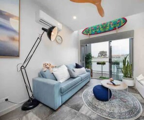 Relax in this stylish living room with a sofa, floor lamp, and blue bean bag chair, offering a view of the outdoors.