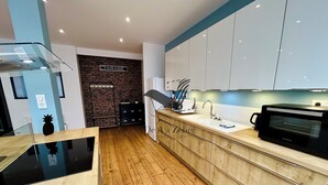 Une cuisine moderne avec un plancher en bois, des armoires blanches et un micro-ondes noir.