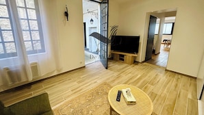 Un salon moderne avec un téléviseur à écran plat, une petite table et un canapé.