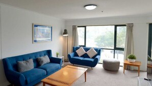 A modern living room with a blue sofa, a matching armchair, and a wooden coffee table.