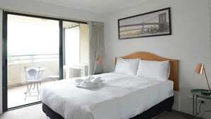 A hotel room with a large bed, a view of the outdoors, and a framed picture on the wall.