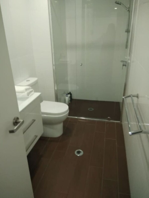 A small, compact bathroom with a toilet, a shower stall, and a sink. - Cosy getaway in the Heart of Braddon (Braddon)