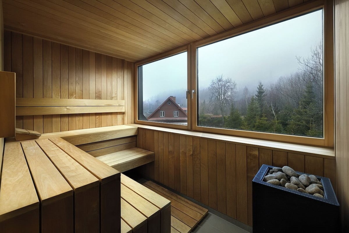 Un sauna con bancos de madera y un ventanal con vistas a una zona residencial.