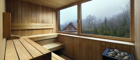 Un sauna con bancos de madera y un ventanal con vistas a una zona residencial.