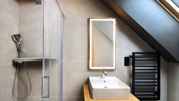 A modern bathroom with a shower, a sink, and a mirror.
