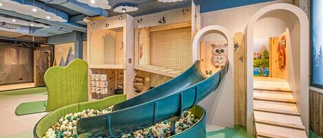 A children's play area with a slide, climbing structures, and a ball pit.