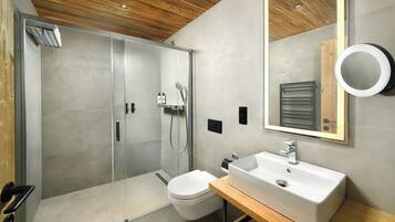 A modern bathroom with a glass-enclosed shower, a white sink, and a wooden vanity.
