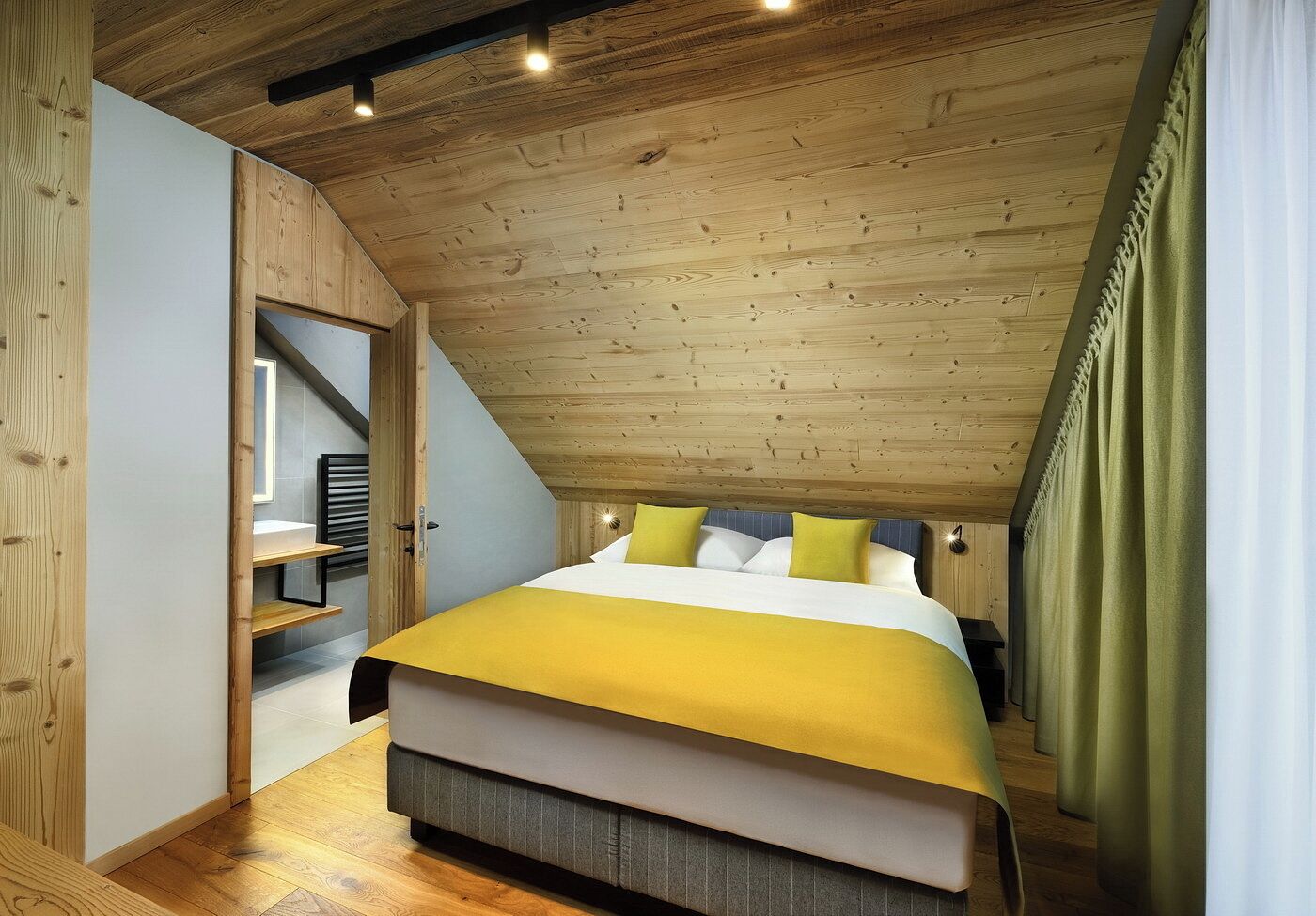 A bedroom with a sloped ceiling, a bed with a yellow bedspread, and a wooden wardrobe.