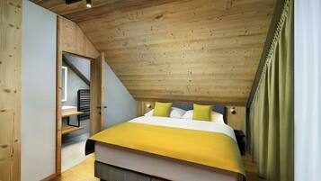 A bedroom with a sloped ceiling, a bed with a yellow bedspread, and a wooden wardrobe.