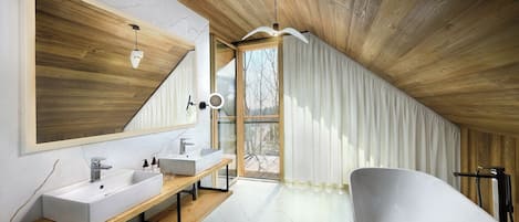 A modern bathroom with a freestanding bathtub, a large mirror, and a wooden vanity.