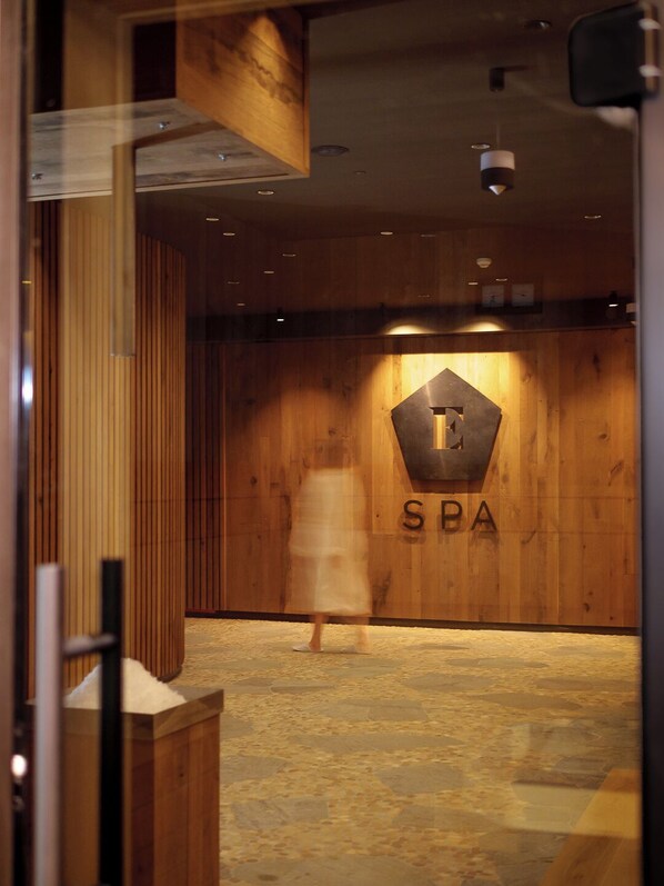 A spa interior with wooden paneling, a stone floor, and a sign with 'SPA' and a stylized 'E'. - Hotel ELEMENTS (Vysoké Tatry)