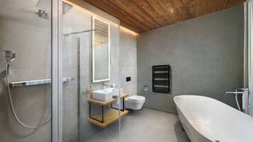 Un baño moderno con ducha envuelta en vidrio, bañera independiente y zona de lavamanos minimalista.